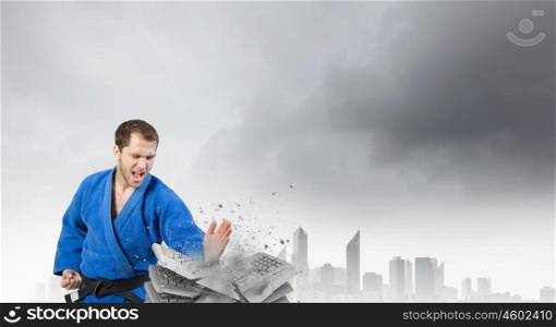 Krate man in action. Determined karate man breaking stack of keyboards