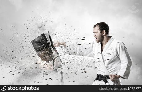 Krate man in action. Determined karate man in white breaking computer