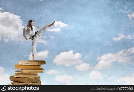 Krate man in action. Determined karate man on pile of old books