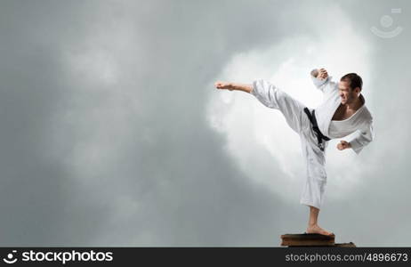 Krate man in action. Determined karate man on pile of old books