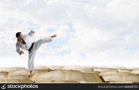 Krate man in action. Determined karate man on pile of old books