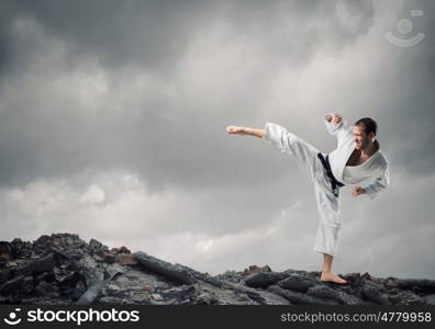 Krate man in action. Karate man in jump against cloudy background