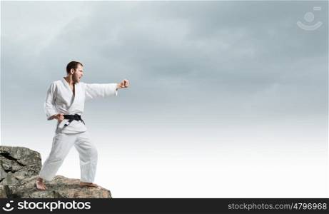 Krate man in action. Karate man in jump against cloudy background