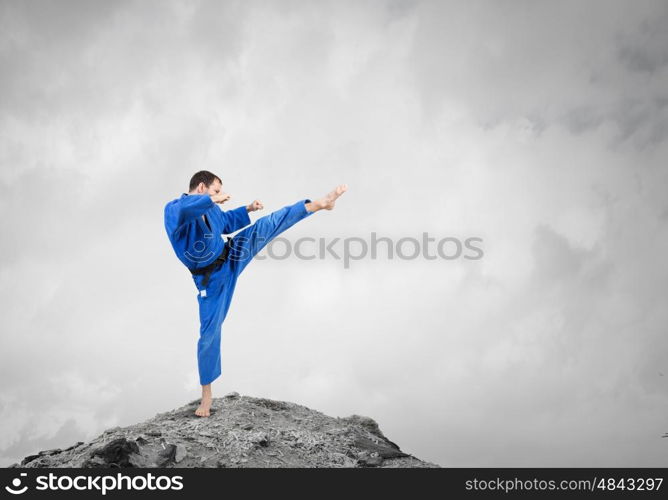 Krate man in action. Karate man in jump against cloudy background