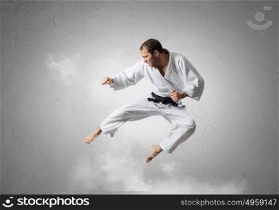 Krate man in action. Karate man in jump against cloudy background