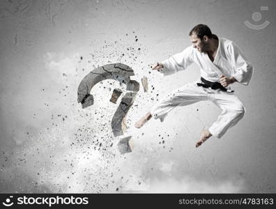 Krate man in action. Karate man in jump breaking question mark