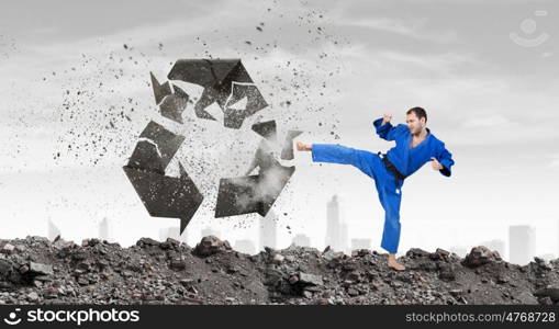 Krate man in action. Karate man in jump breaking recycle stone sign