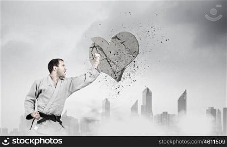 Krate man in action. Karate man in jump breaking stone love heart