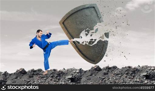 Krate man in action. Karate man in jump breaking stone shield