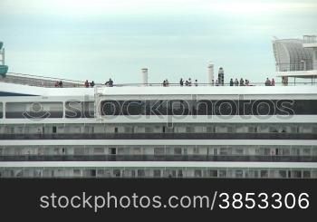 Kreuzfahrttouristen auf einem Schiff beim Auslaufen - cruis ship passengers standing on the top deck