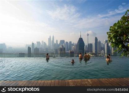 KUALA LUMPUR, MALAYSIA : FEBRUARY 21, 2019 : Vacation in Kuala-Lumpur. Young woman enjoy swimming in roof top pool with beautiful city view