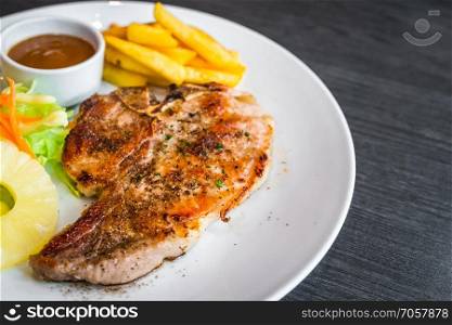kurobuta pork chop with vegetable and french fries in white dish.