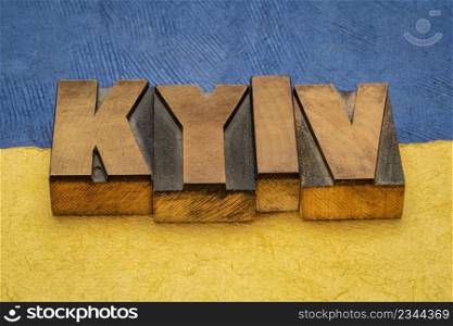 Kyiv, capitol of Ukraine, word abstract in vintage letterpress wood type printing blocks against paper abstract in colors of Ukrainian national flag, blue and yellow