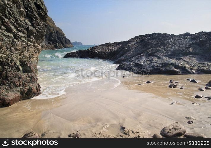 Kynance Cove beach with tide coming in. Golden sand beach with blue sky and tide coming in