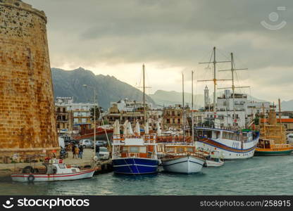 Kyrenia or Girne historical city center, view to marina with many yachts and boats with Venetian castle walls and mountains in the background, North Cyprus