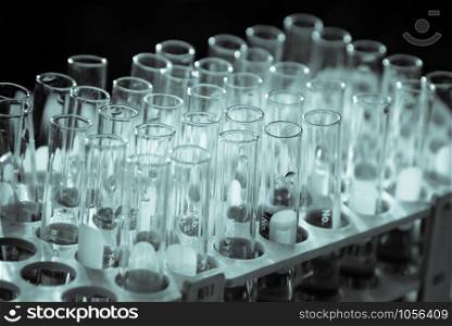 Lab science research glass items adding drop to one of several test tubes. A scientific experiment in a science research Laboratory.