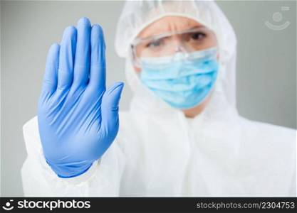 Lab scientist doctor wearing biohazard protective suit hand gesturing STOP Coronavirus COVID-19 / 2019-ncov / SARS-CoV-2 disease global pandemic outbreak,restrictive no entry quarantine order,stay out