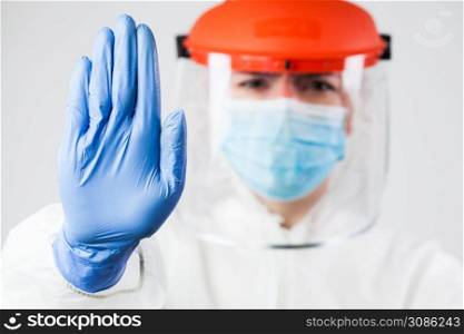 Lab scientist EMS ICU doctor wearing N95 biohazard PPE protective suit raised hand gesturing STOP Coronavirus 2019-ncov SARS-CoV-2 disease global pandemic outbreak,restrictive no entry quarantine zone