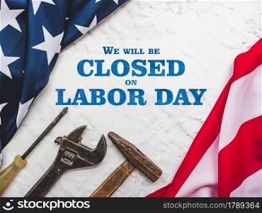 LABOR DAY. Hand tools and the Flag of the United States of America lying on the table. View from above, close-up. Congratulations to family, relatives, friends and colleagues. National holiday concept. LABOR DAY. Hand tools and the Flag of the United States of America