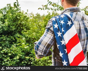 LABOR DAY. Hand tools lying on the table. View from above, close-up. Preparing for the celebration. Congratulations to loved ones, family, relatives, friends and colleagues. National holiday concept. Handsome man holding US flag in his hands