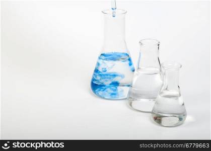 Laboratory equipment and color chemicals on white background