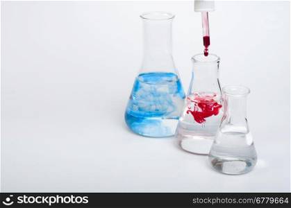 Laboratory equipment and color chemicals on white background