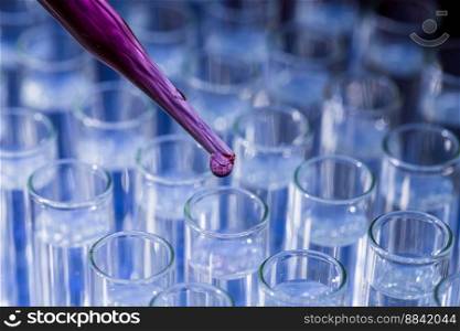 Laboratory glassware with pipette dropping red pink fluid into test tube