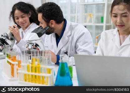 Laboratory research scientist team working on medical experiments by use of microscope and scientific data analysis on laptop.