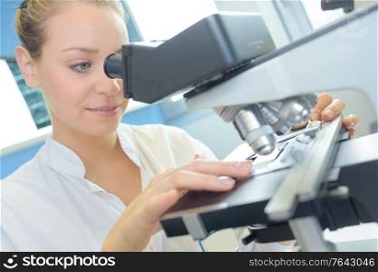 laboratory technician observing through a microscope