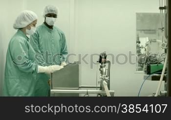 Laboratory technicians at work in medical plant with machinery and computer