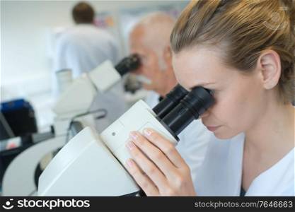 Laboratory worker looking into microscope eyepiece