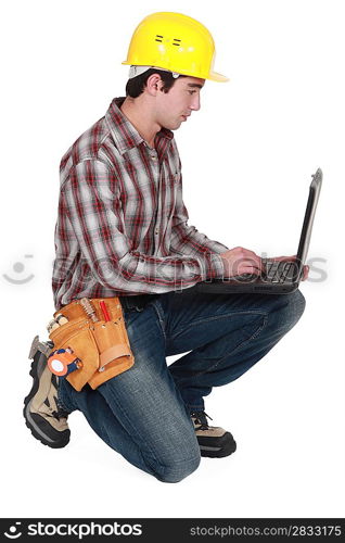 Laborer kneeling with computer