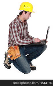 Laborer kneeling with computer