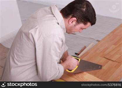Laborer sawing laminate floor