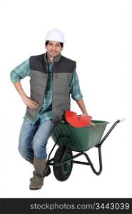 Labourer posing with a wheelbarrow and spade
