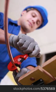 Labourer using tool to prepare copper pipe