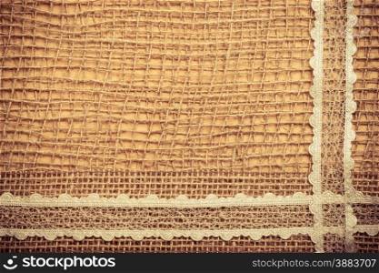 Lace frame on natural mesh material, brown burlap cloth background. Retro vintage style
