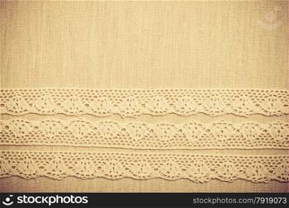 Lace ribbon on natural linen, bright cloth fabric background. Border frame. vintage style