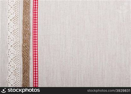 Lace, rope and red ribbon frame on natural linen, bright cloth fabric background. Retro style