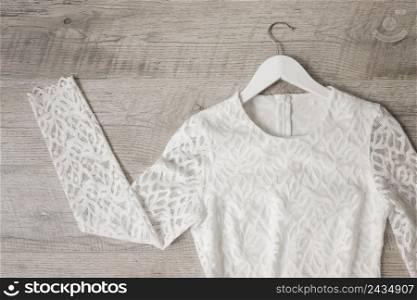 lace white wedding dress coat hanger against wooden textured background