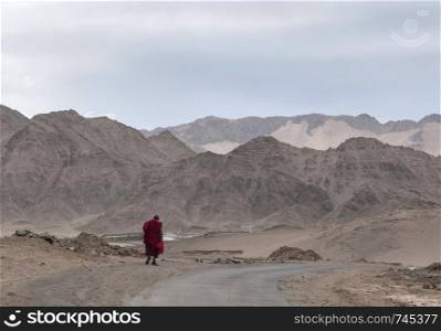 LADAKH, INDIA, July 2013, Monk walking with mountain backdrop.. LADAKH, INDIA, July 2013, Monk walking with mountain backdrop