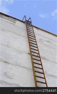 Ladder at a wall. An old, rusty ladder at a concrete wall