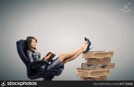 Lady boss. Young attractive businesswoman reading book in chair