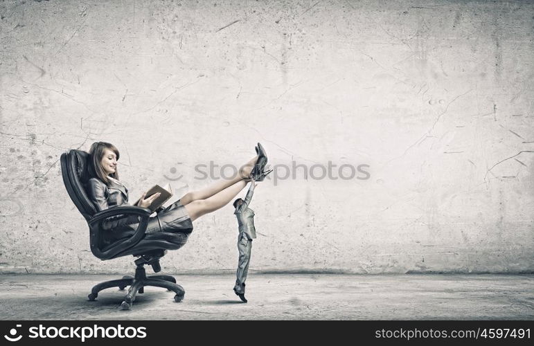 Lady boss. Young attractive businesswoman reading book in chair