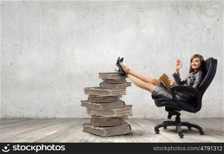 Lady boss. Young attractive businesswoman reading book in chair