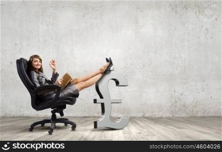 Lady boss. Young attractive businesswoman sitting in chair and reading book