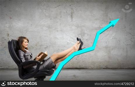 Lady boss. Young attractive businesswoman sitting in chair and reading book