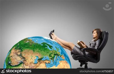 Lady boss. Young attractive businesswoman sitting in chair and reading book. Elements of this image are furnished by NASA