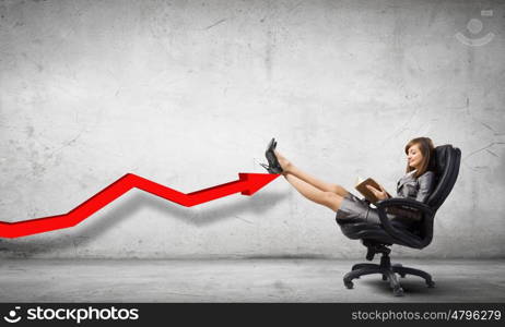 Lady boss. Young attractive businesswoman sitting in chair and reading book