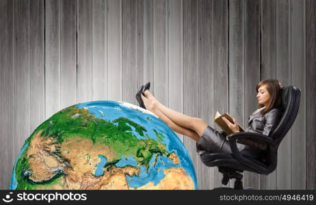 Lady boss. Young attractive businesswoman sitting in chair and reading book. Elements of this image are furnished by NASA